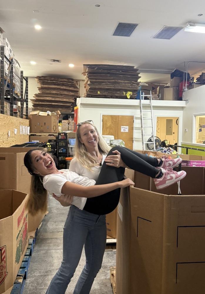 Two board members laughing together between sorting boxes